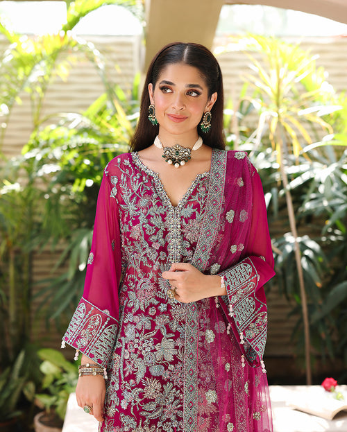 Woman wearing magenta embroidered chiffon suit with sequinned floral panels and organza daman border